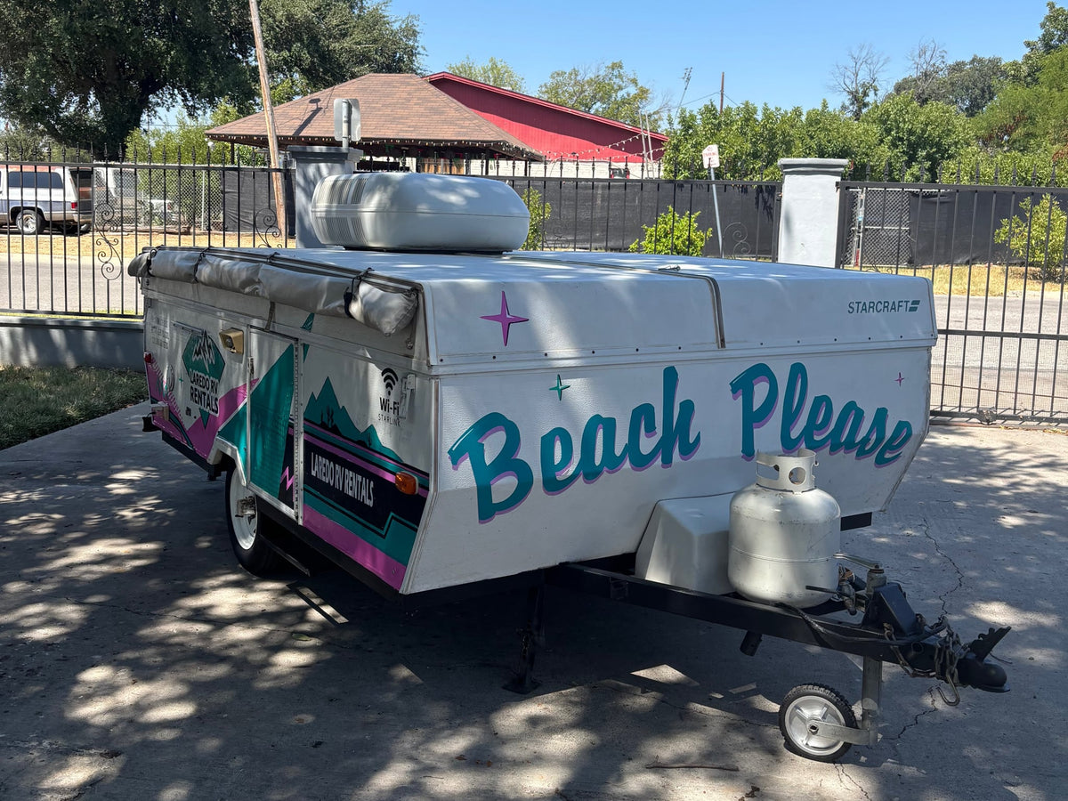 This colorful pop-up camper from an RV rental service features "Beach Please" art — photo 1