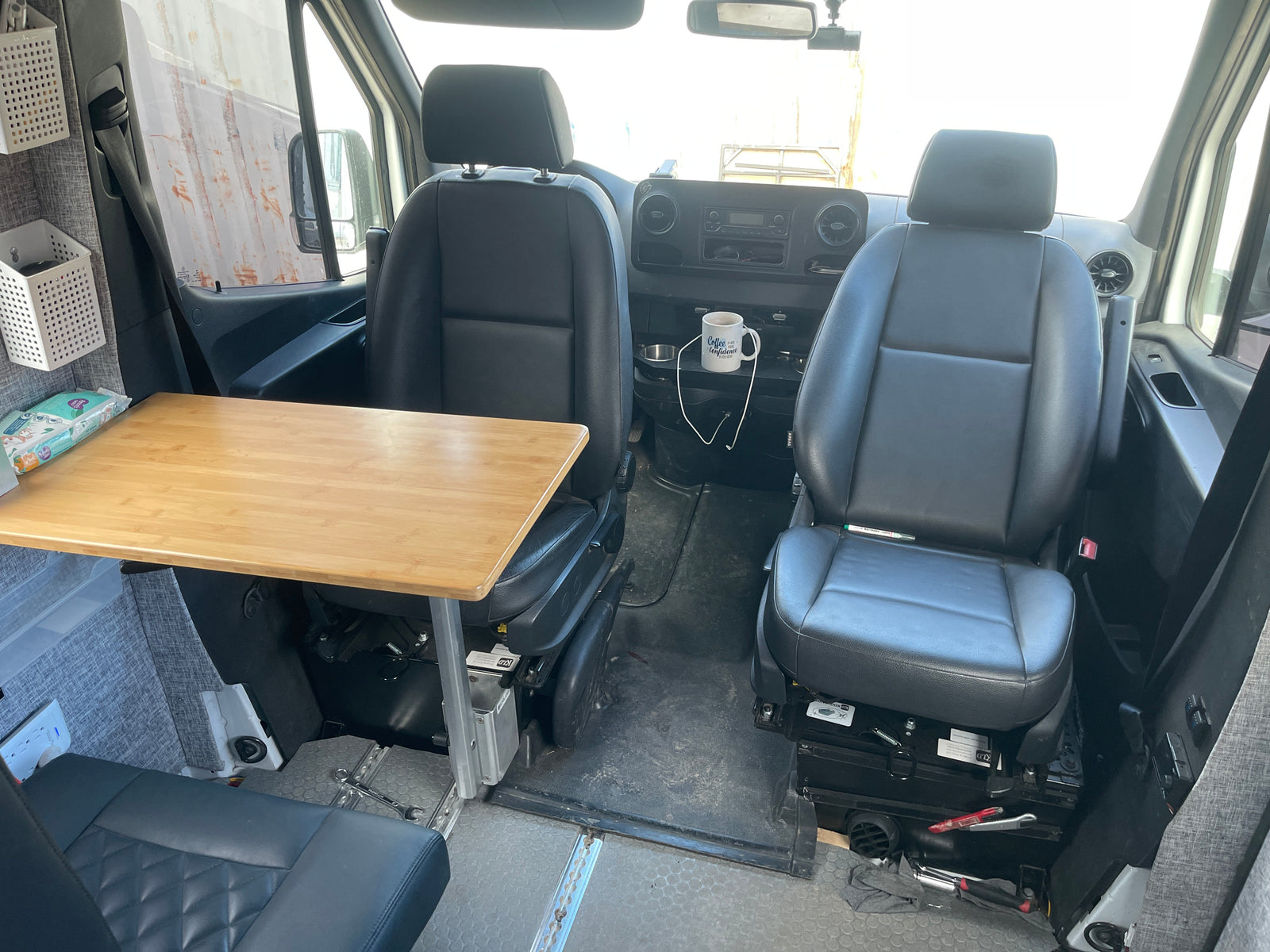 This RV rental interior features swiveling front seats, a bamboo table, and convenient storage for comfortable travel.