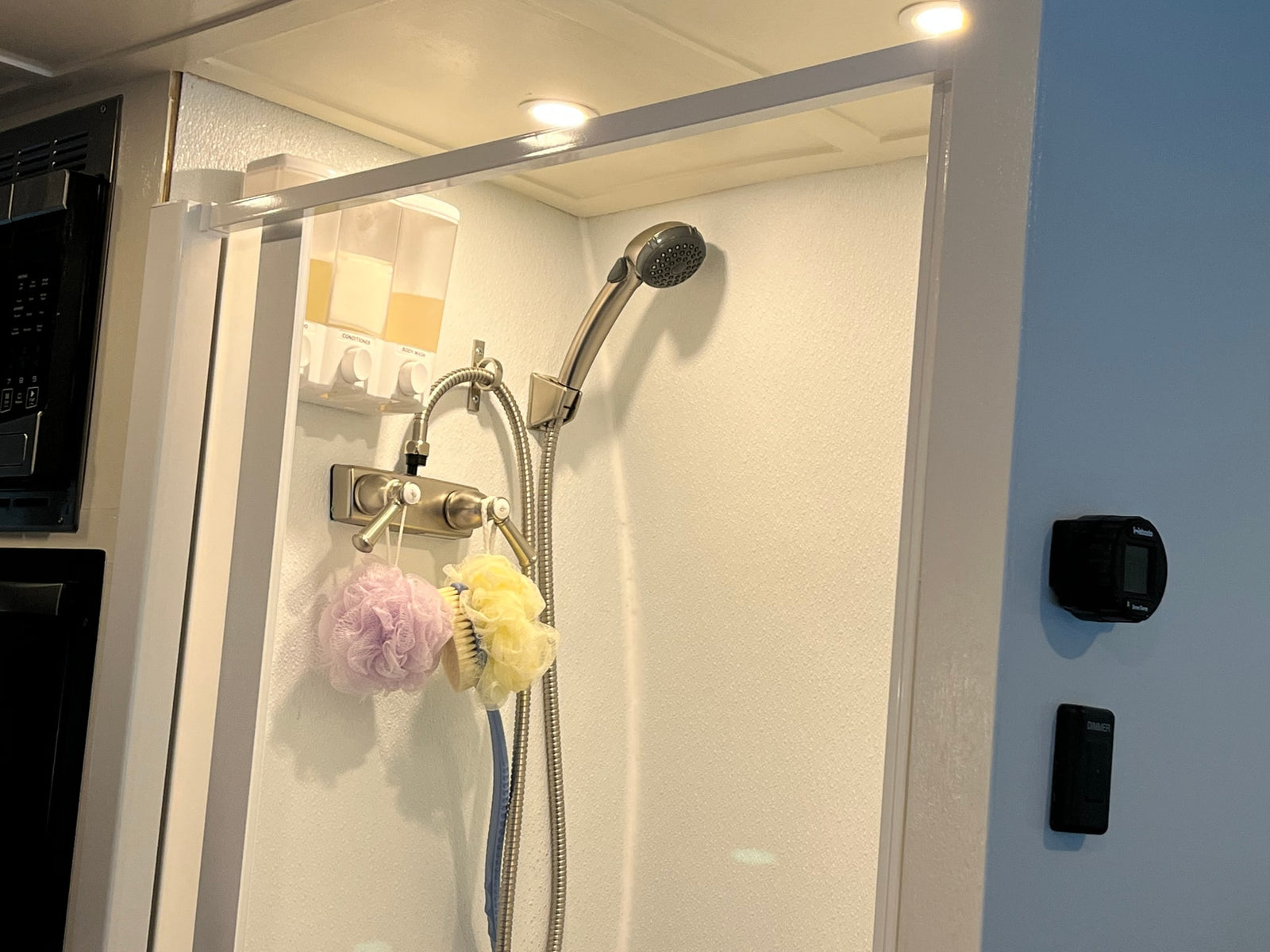 Compact RV rental shower featuring wall-mounted soap dispensers, loofahs, and shower controls for a convenient travel experience.