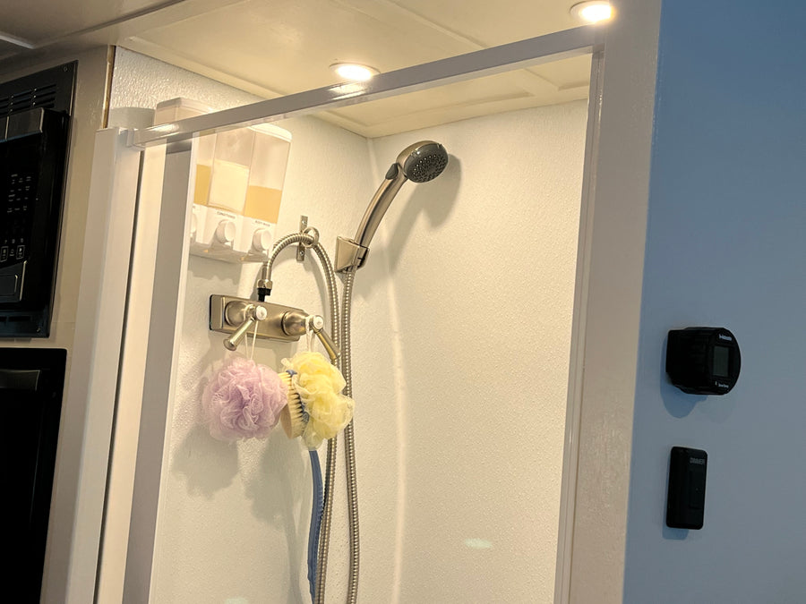 Compact RV rental shower featuring wall-mounted soap dispensers, loofahs, and shower controls for a convenient travel experience.