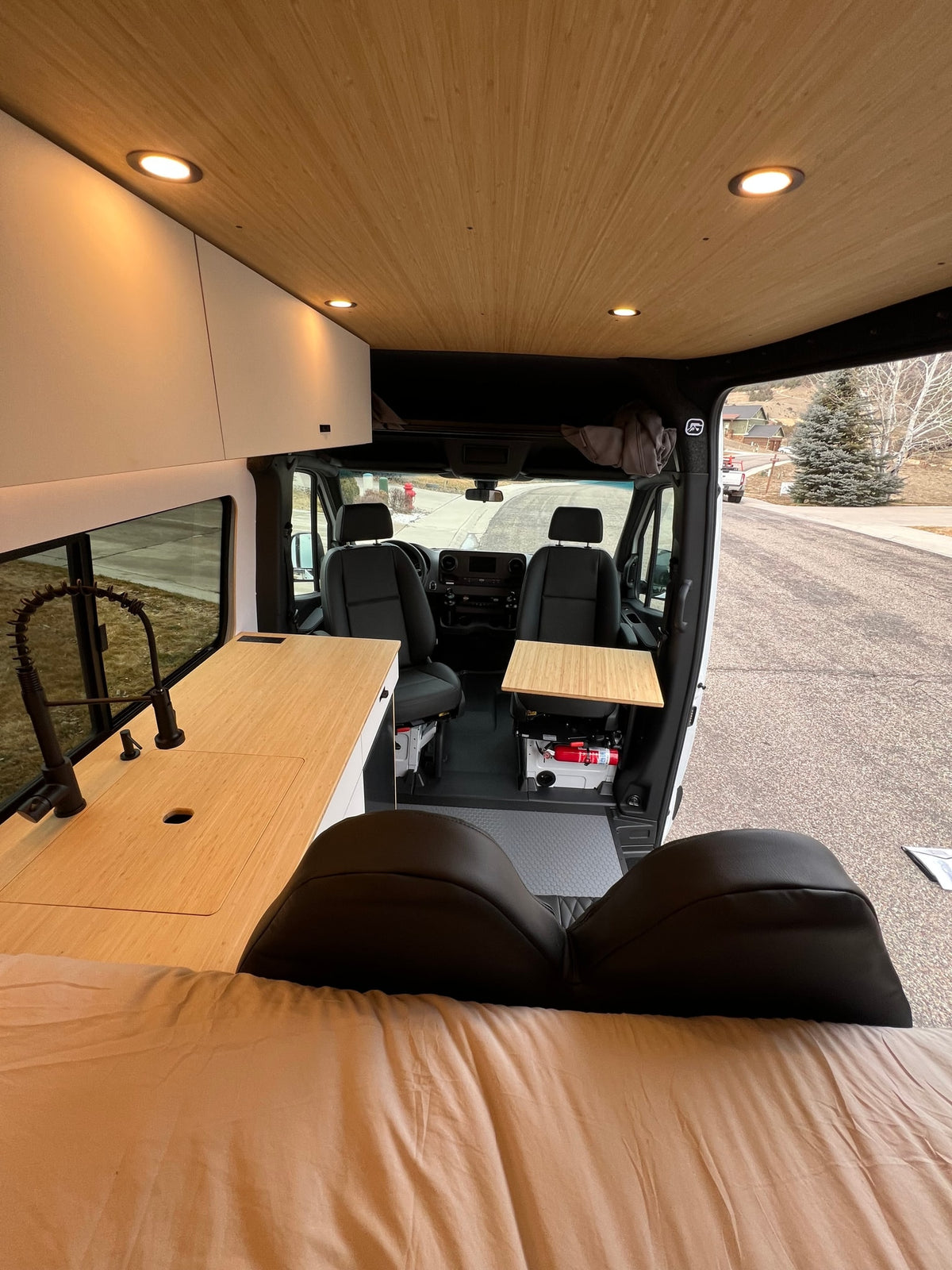 Spacious rv rental camper van interior: modern kitchen, comfortable bed, and accessible front cabin area with table. — photo 10