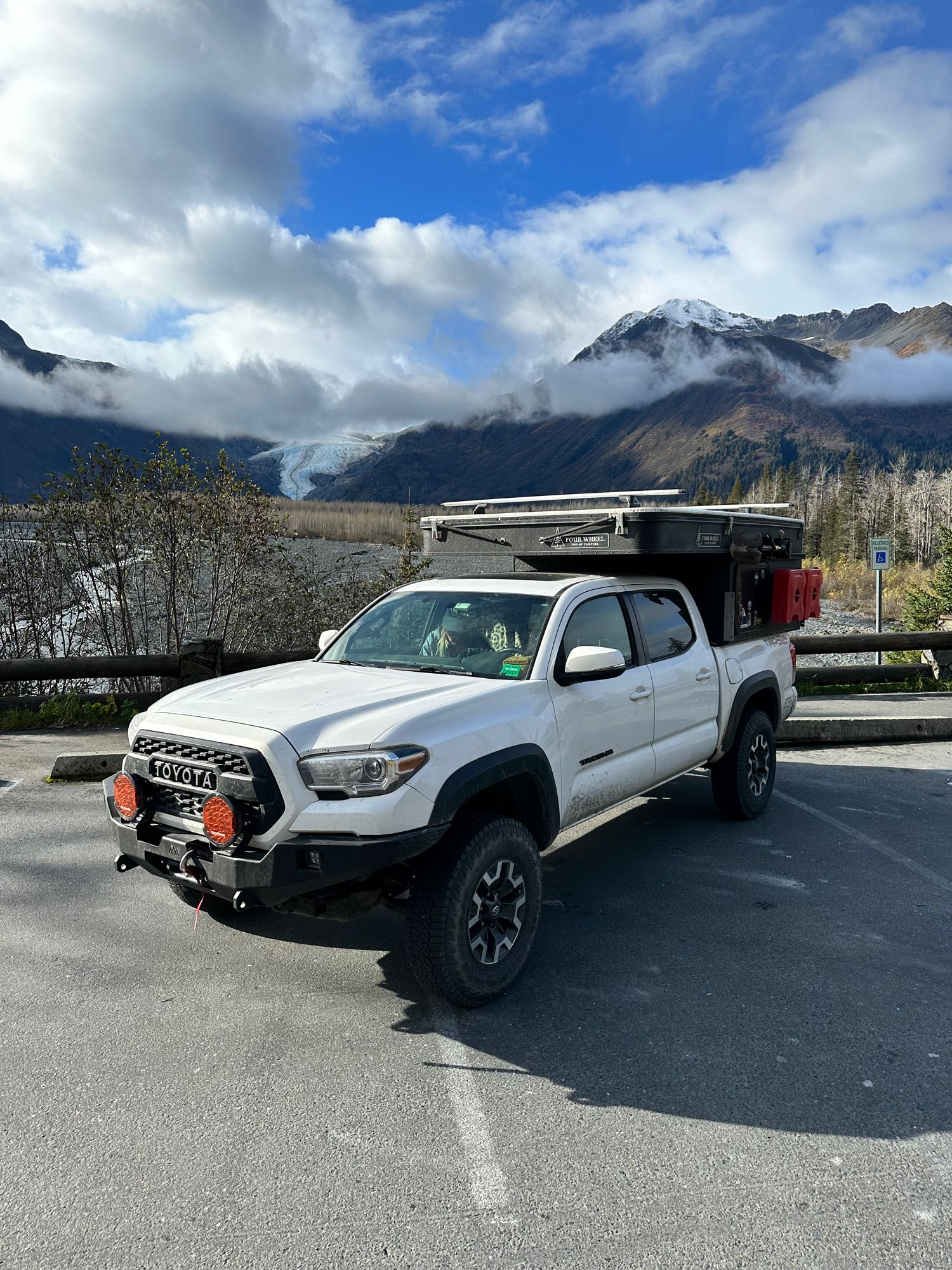 and picnic table.|White truck camper on sandy beach at sunset