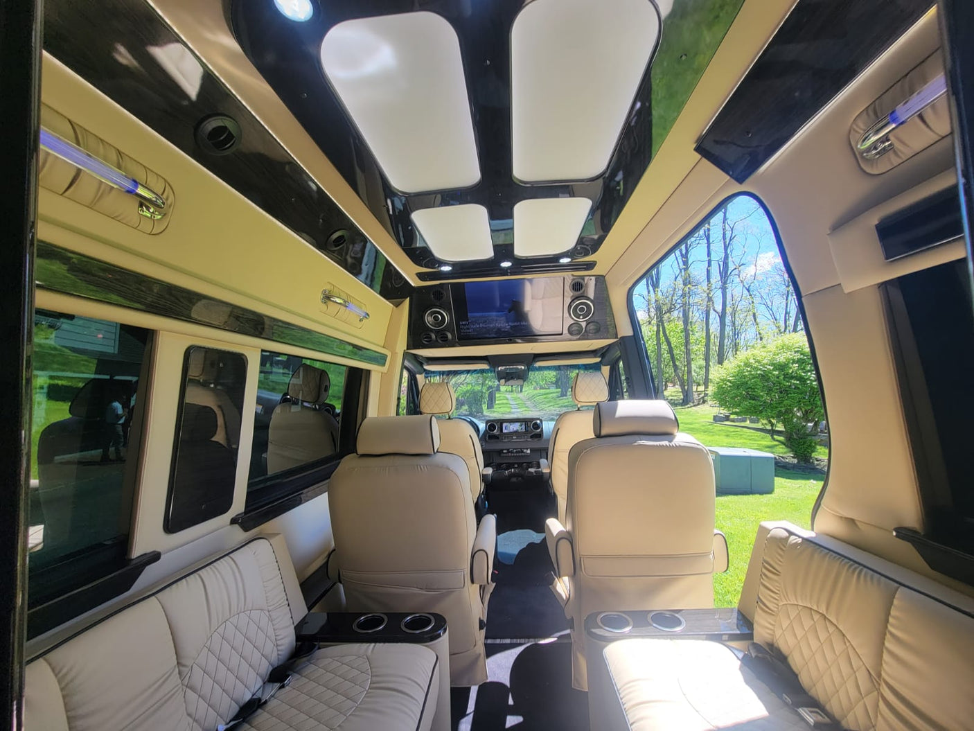 Luxurious RV rental interior with cream leather seats, shiny trim, and a large screen, showing a spacious cabin.
