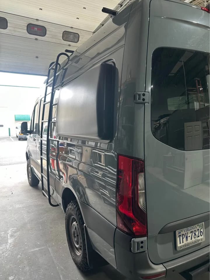 on dirt. Features a ladder and roof tech for off-grid travel & van life adventures.|Your RV rental view: a serene lake with misty reflections of a snow-capped mountain at dawn.|Grey Sprinter adventure van