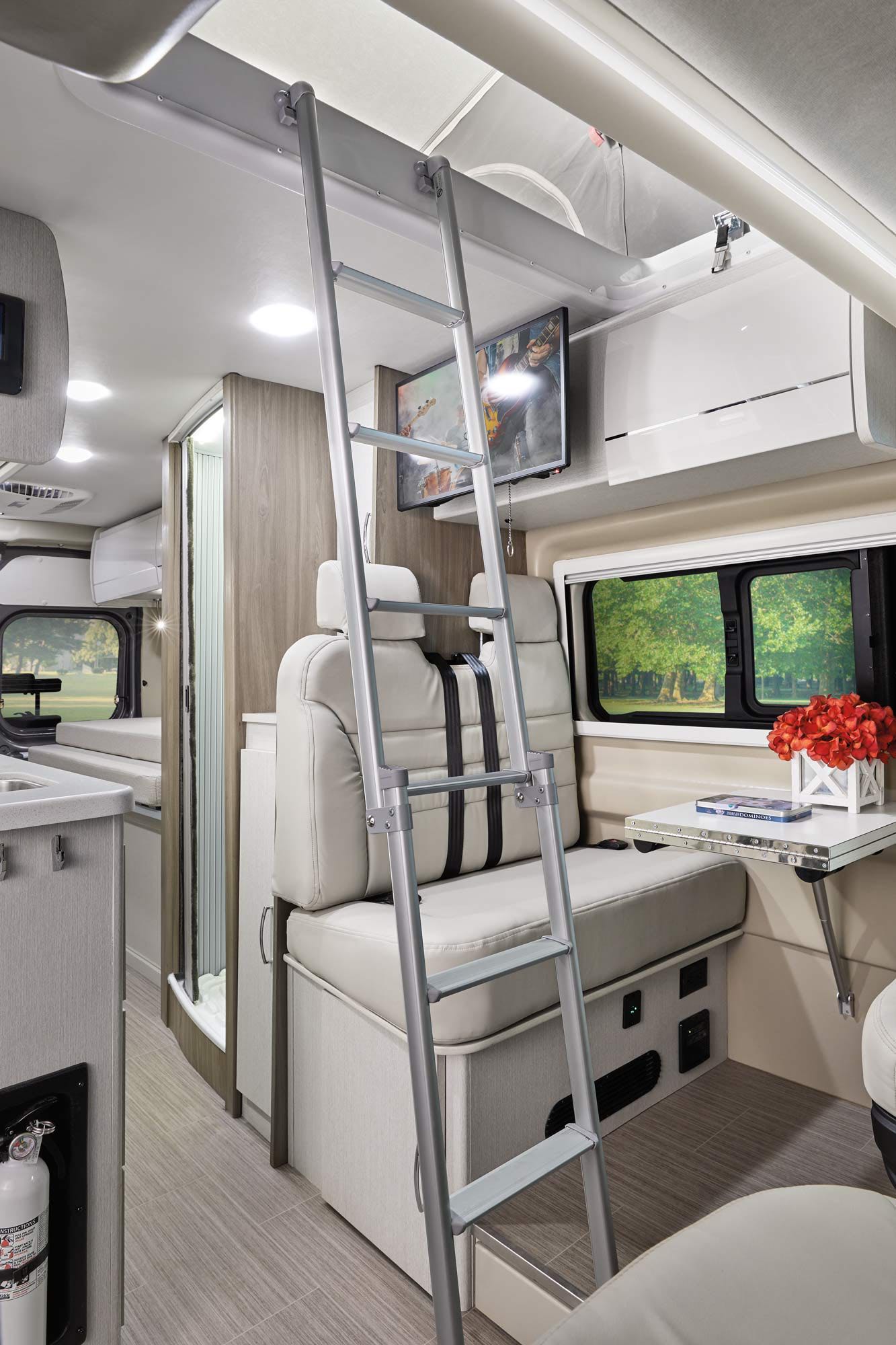 Modern rv rental interior: features ladder to upper bunk, dinette, TV, kitchen, and shower for ultimate camper comfort.