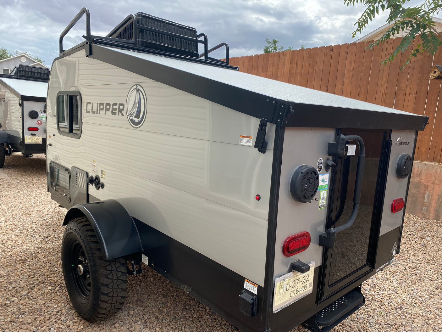 A grey Coachmen Clipper off-road camper, possibly an RV rental, parked on gravel with a Utah temporary plate visible.