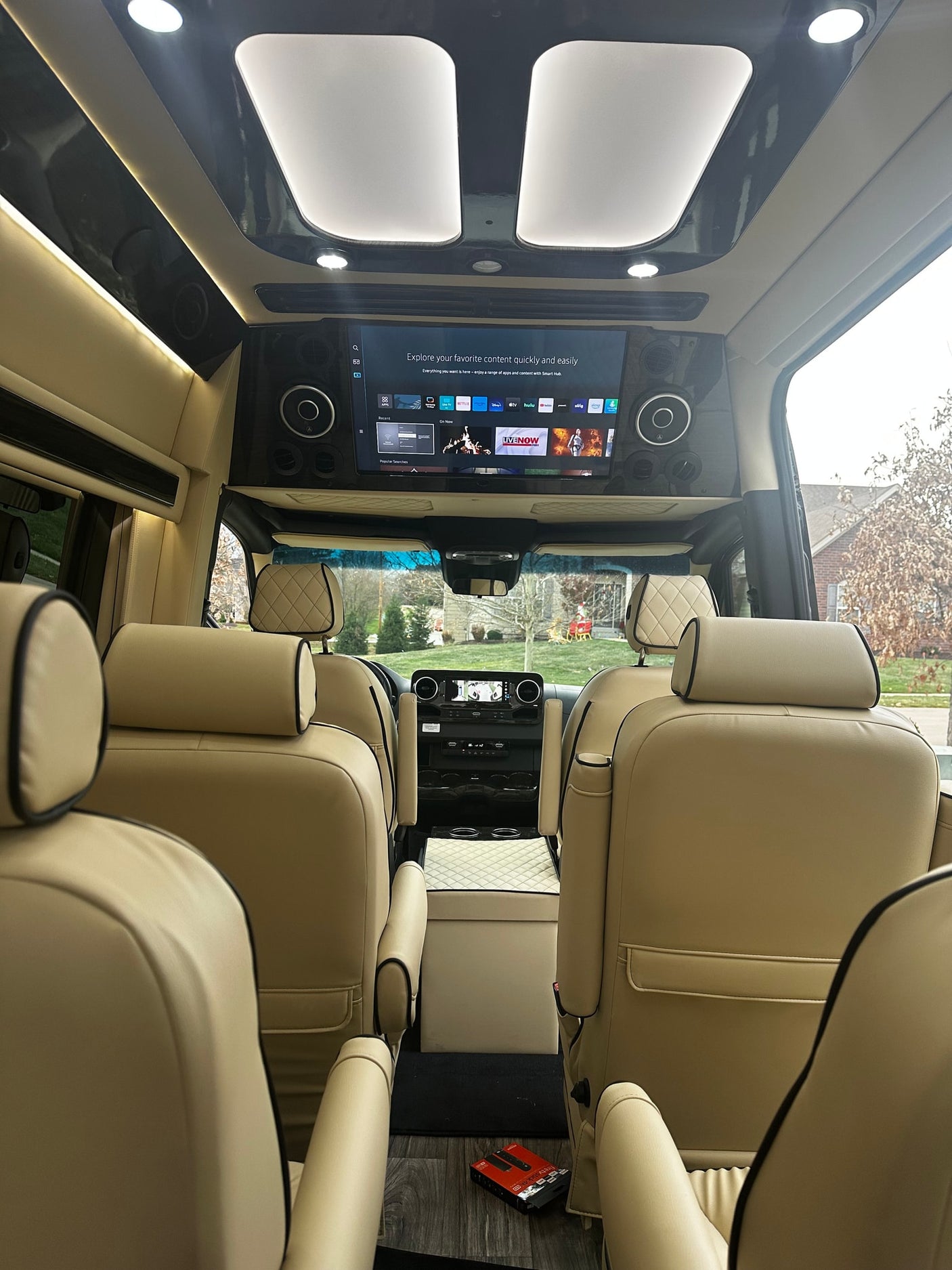 and dark flooring.|Luxury RV rental interior featuring premium cream seats and a well-appointed driver's area for comfortable travel.|RV rental control panel: smart display in luxury van interior shows lighting
