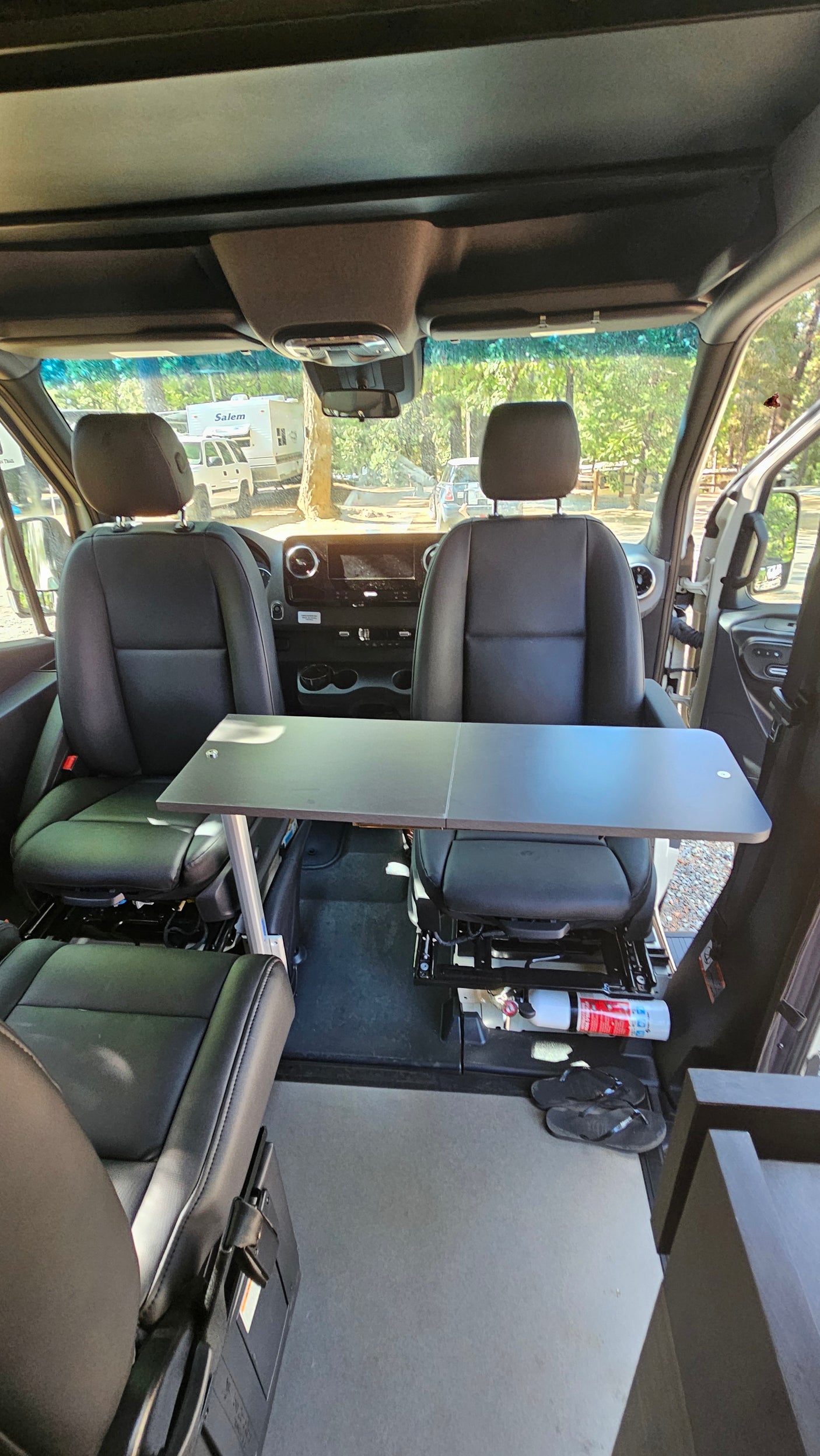 This RV rental shows a camper van interior with front swivel seats, a table, and a fire extinguisher, ideal for a mobile workspace.