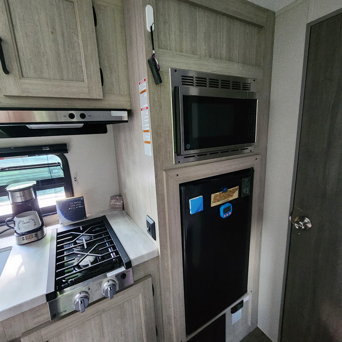 RV rental kitchen: This cozy interior features a microwave, stove, fridge, and coffee maker, perfect for your travels.