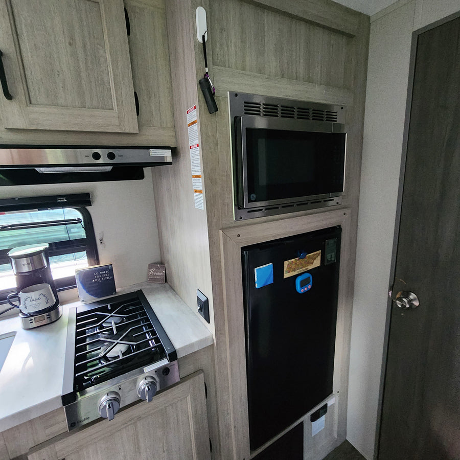 RV rental kitchen: This cozy interior features a microwave, stove, fridge, and coffee maker, perfect for your travels.