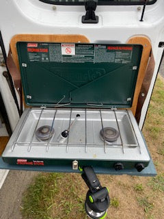 Coleman 2-burner camping stove, part of an RV rental's outdoor kitchen setup for campsite cooking.