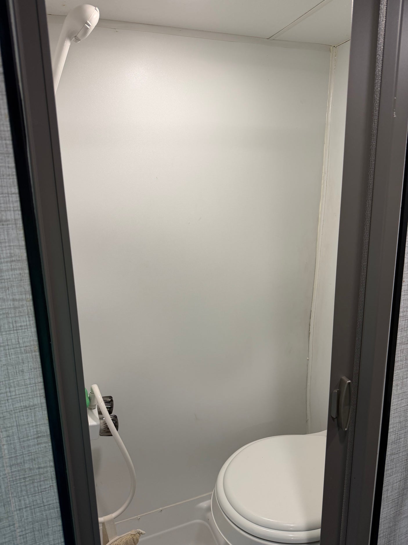 Compact RV rental bathroom with shower and toilet, offering essential amenities in a small space for convenience.