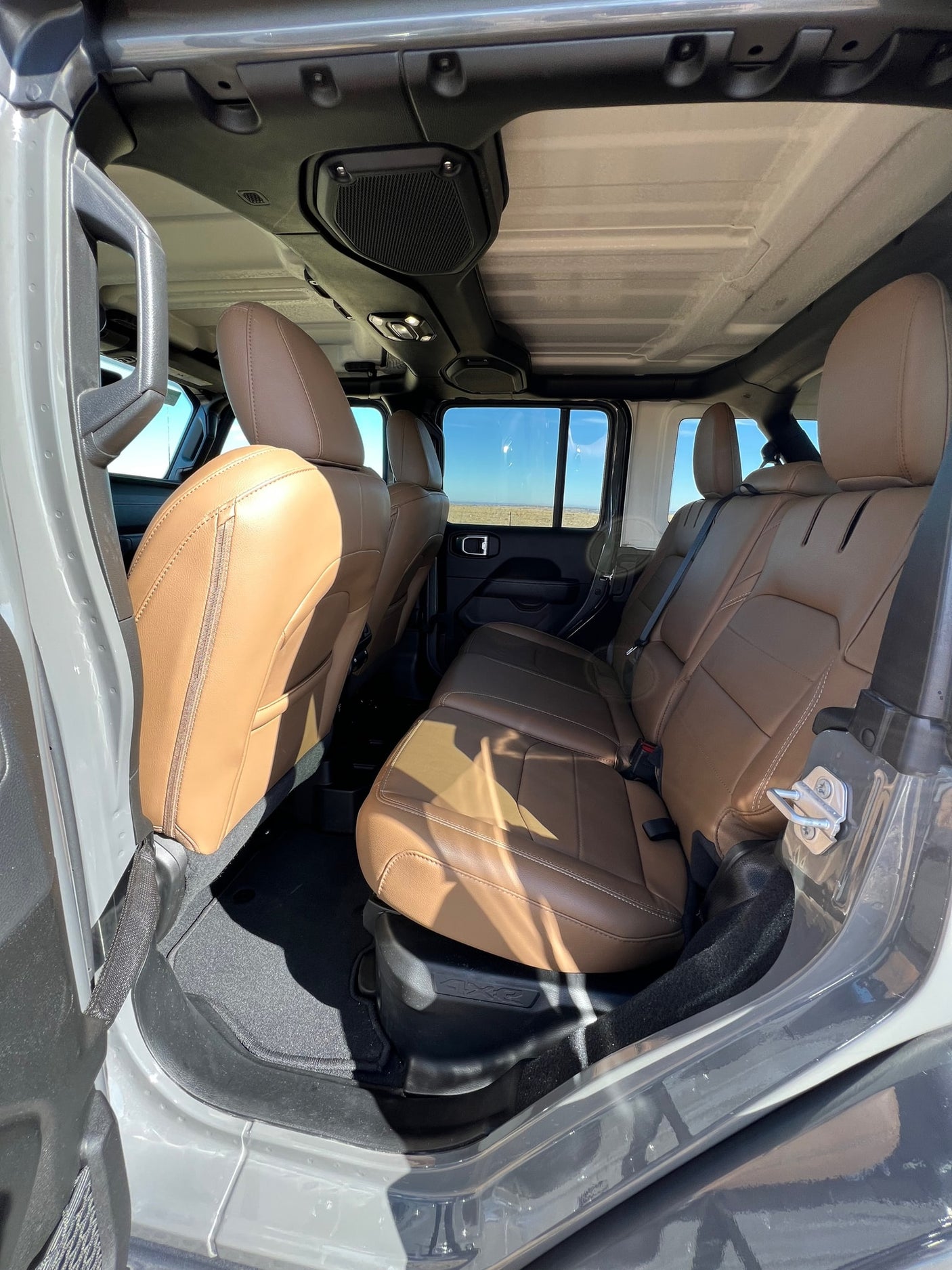 Spacious tan leather interior of a 4x4 SUV, with rear seats & hardtop. Consider this for your next RV rental adventure.