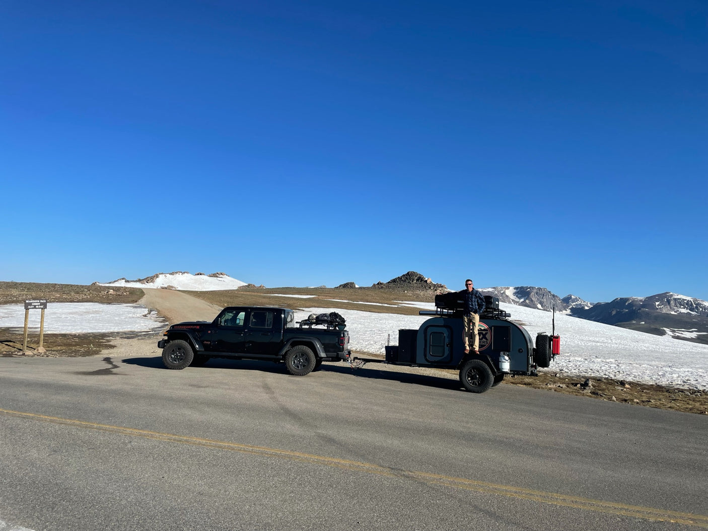 a compact trailer parked on sand beside the ocean