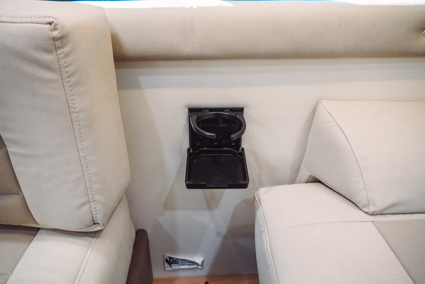 Beige RV rental interior showing comfortable upholstered seating and a black, folding cup holder mounted on the wall. — photo 15