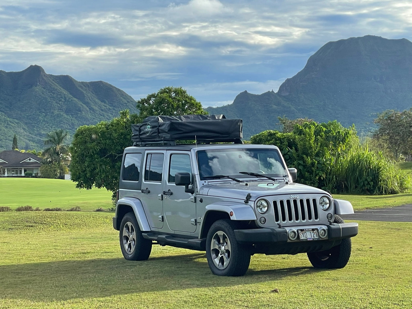 Adventure awaits! Silver Jeep with rooftop tent for your RV rental journey, set against stunning Kauai mountains.