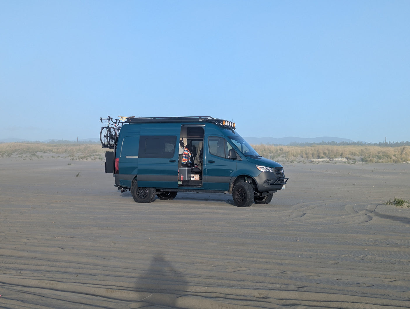 This teal adventure van, an ideal RV rental, is perfectly set up for beach camping with its bike and roof lights.