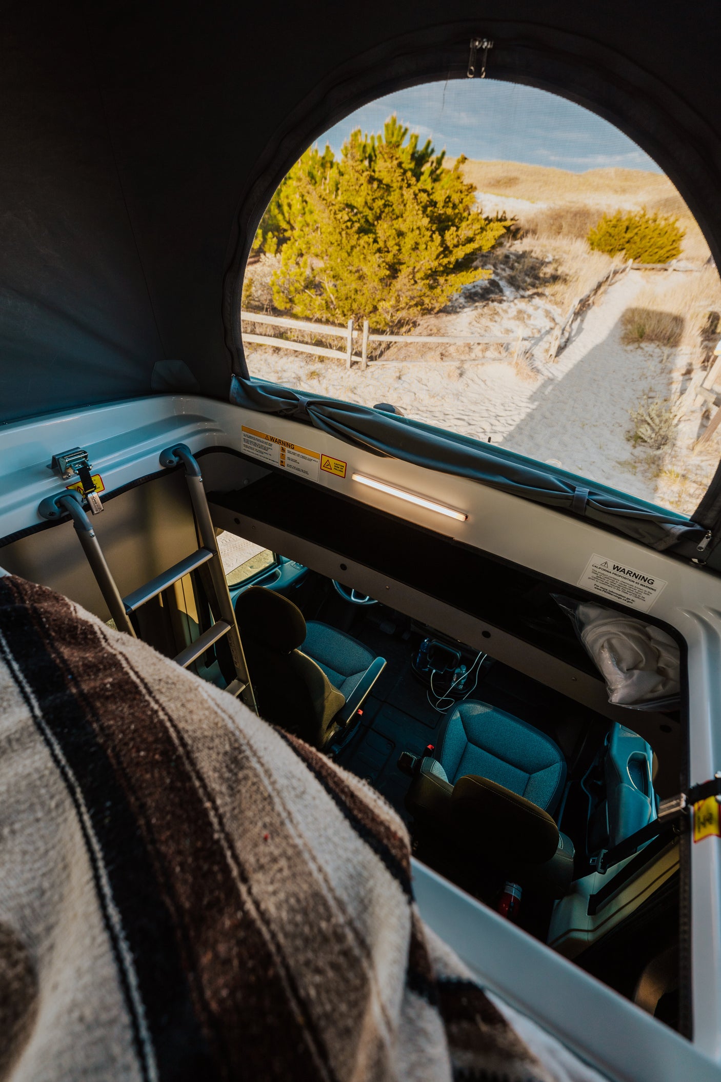 Cozy RV rental interior with pop-top roof open to beach views. Perfect for road trip adventures!