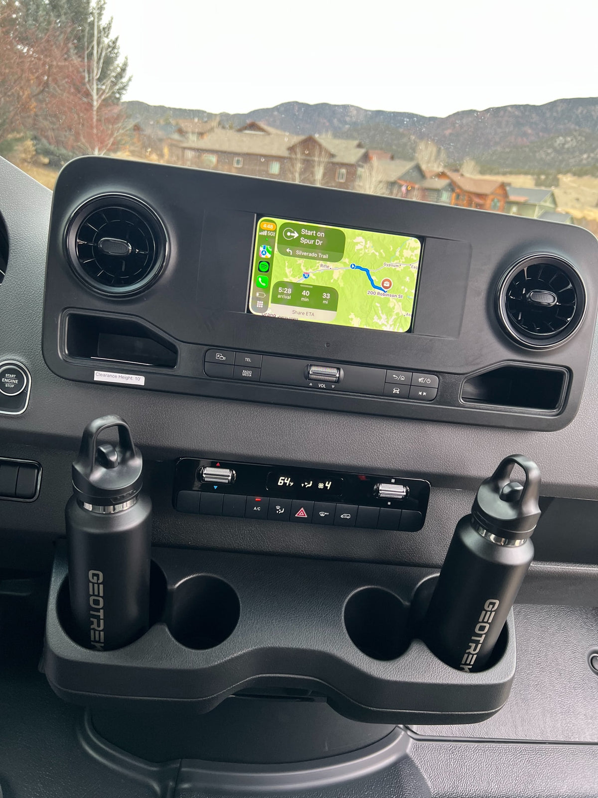 RV rental dashboard with navigation display for a mountain road trip. Features 10' clearance notice & hydration bottles. — photo 6