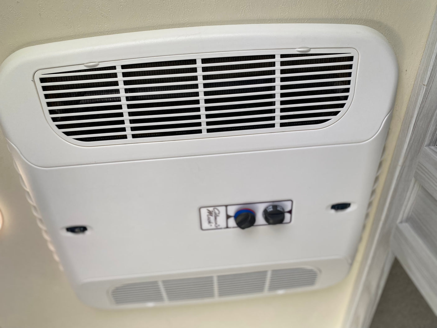 RV rental ceiling-mounted air conditioner with visible grilles and easy-to-use temperature/fan controls for cooling.