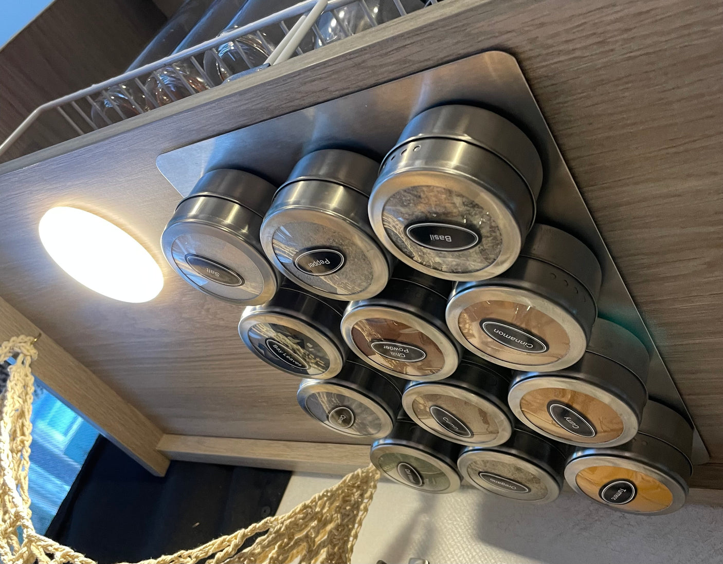 RV rental kitchen featuring a magnetic spice rack mounted under a cabinet, offering space-saving organization for various spices.