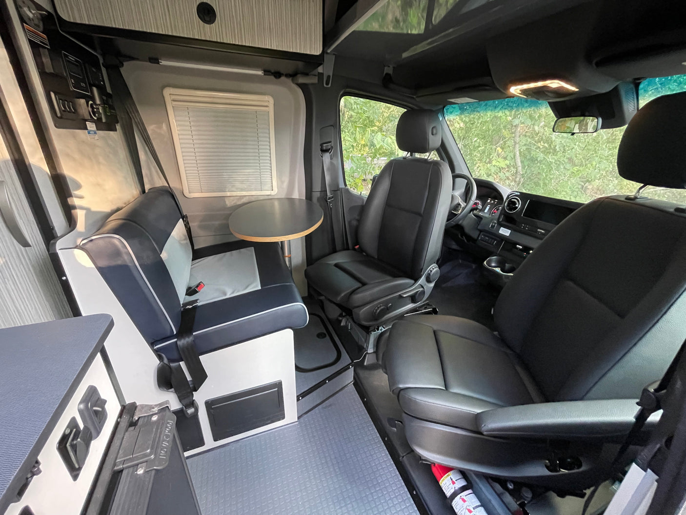 Explore this versatile rv rental interior: dining area with bench, swiveling front seats, overhead storage, and controls.