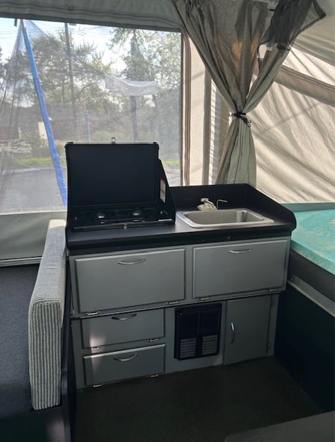 wooded campsite.|Pop-up camper rv rental interior: dinette