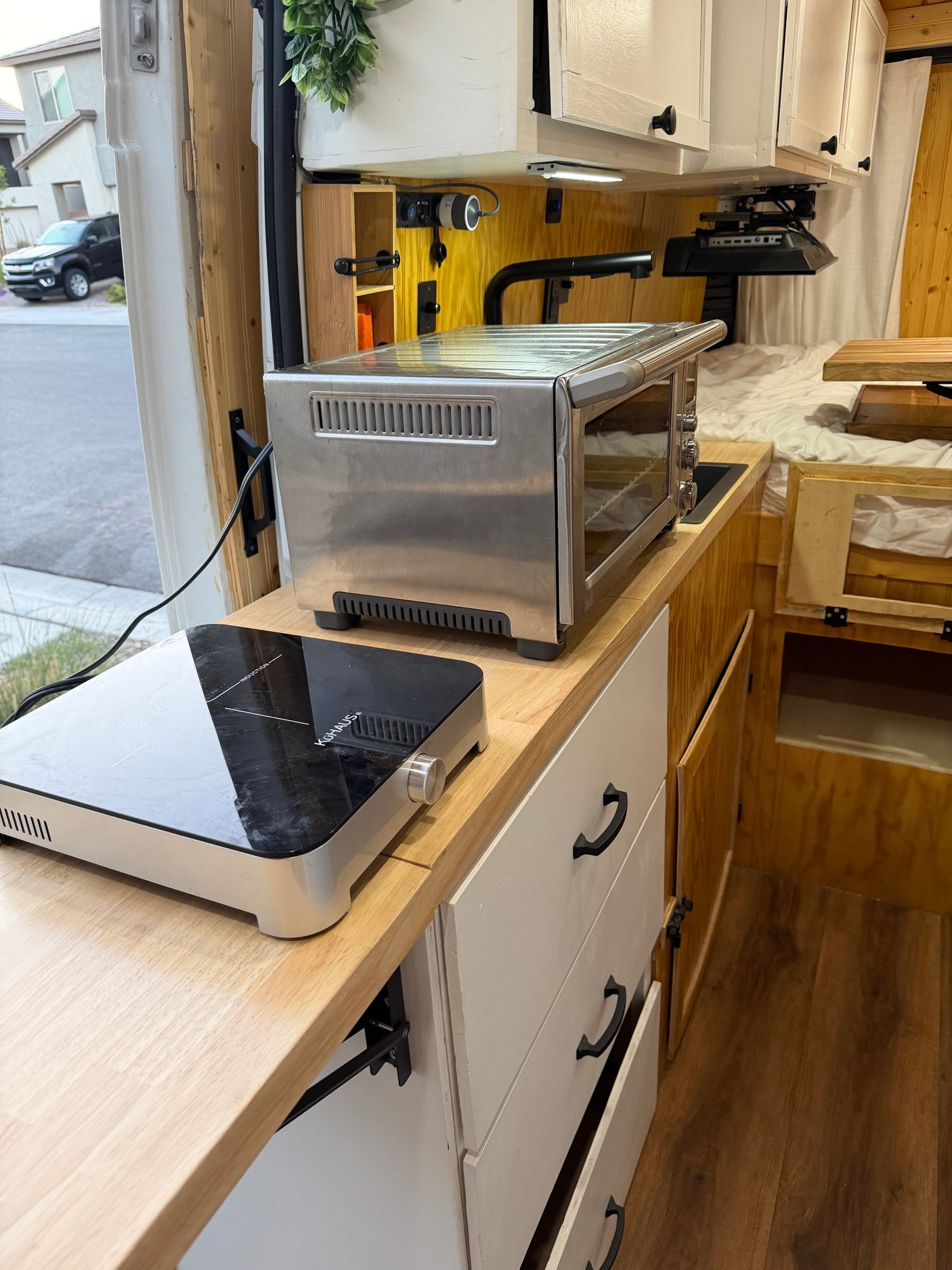 Functional RV rental kitchen with induction cooktop & toaster oven on a light wood counter for compact living.