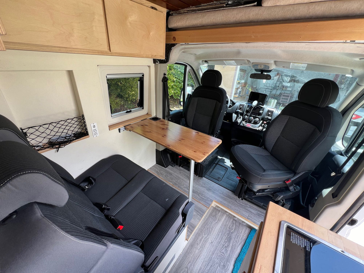 Spacious RV rental interior: a modern camper van with a convertible dining area, multiple seats, and overhead storage for mobile living.