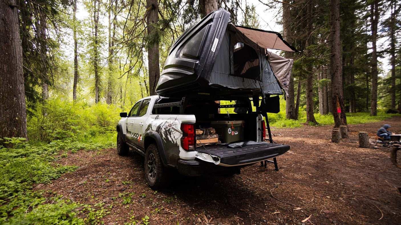like an RV rental for wilderness adventures.|An RV rental setup: truck with rooftop tent and tailgate kitchen