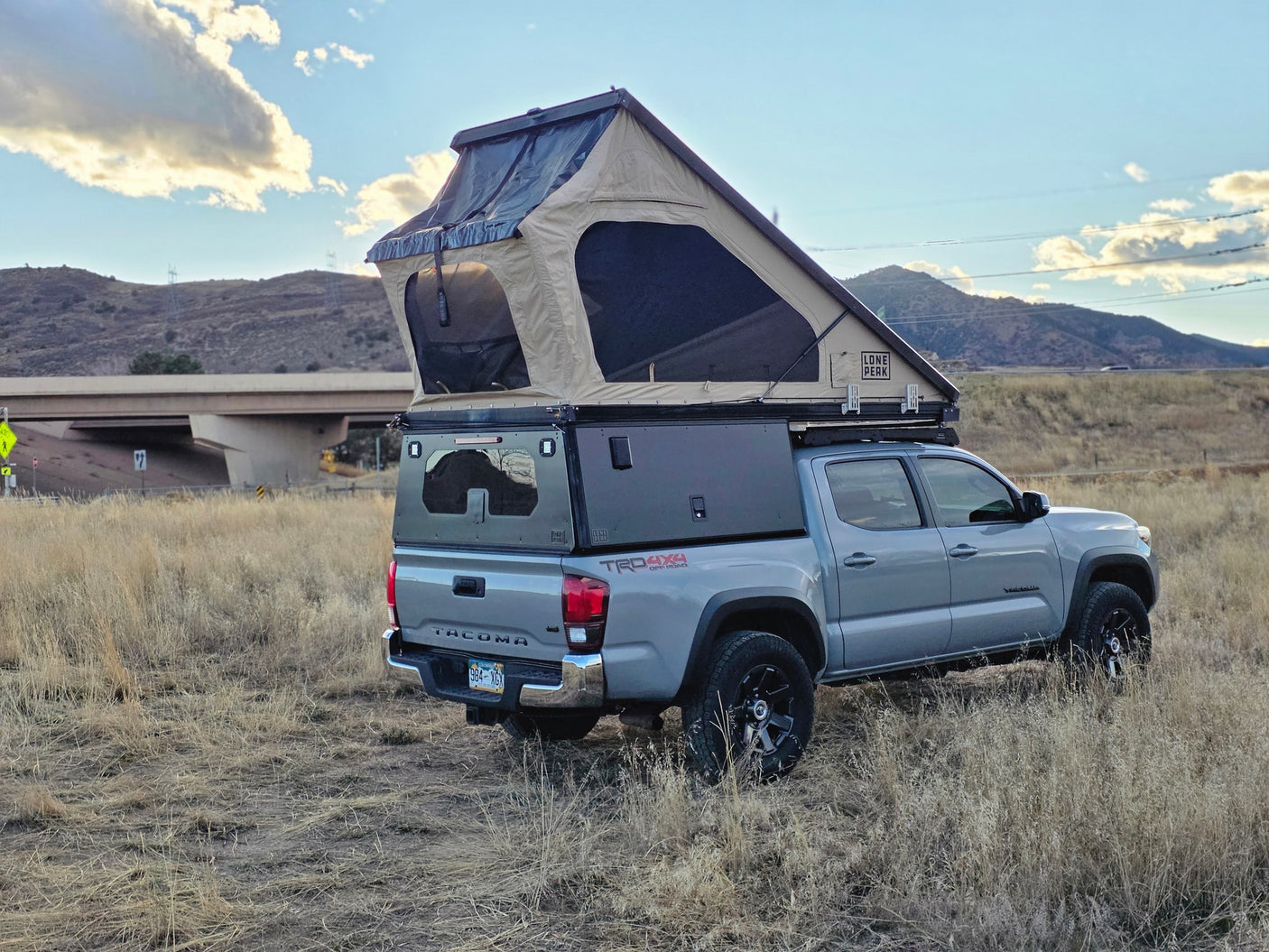 This adventure-ready Toyota Tacoma TRD 4x4 with a rooftop tent and bed cap is perfect for your next rv rental trip in the mountains!