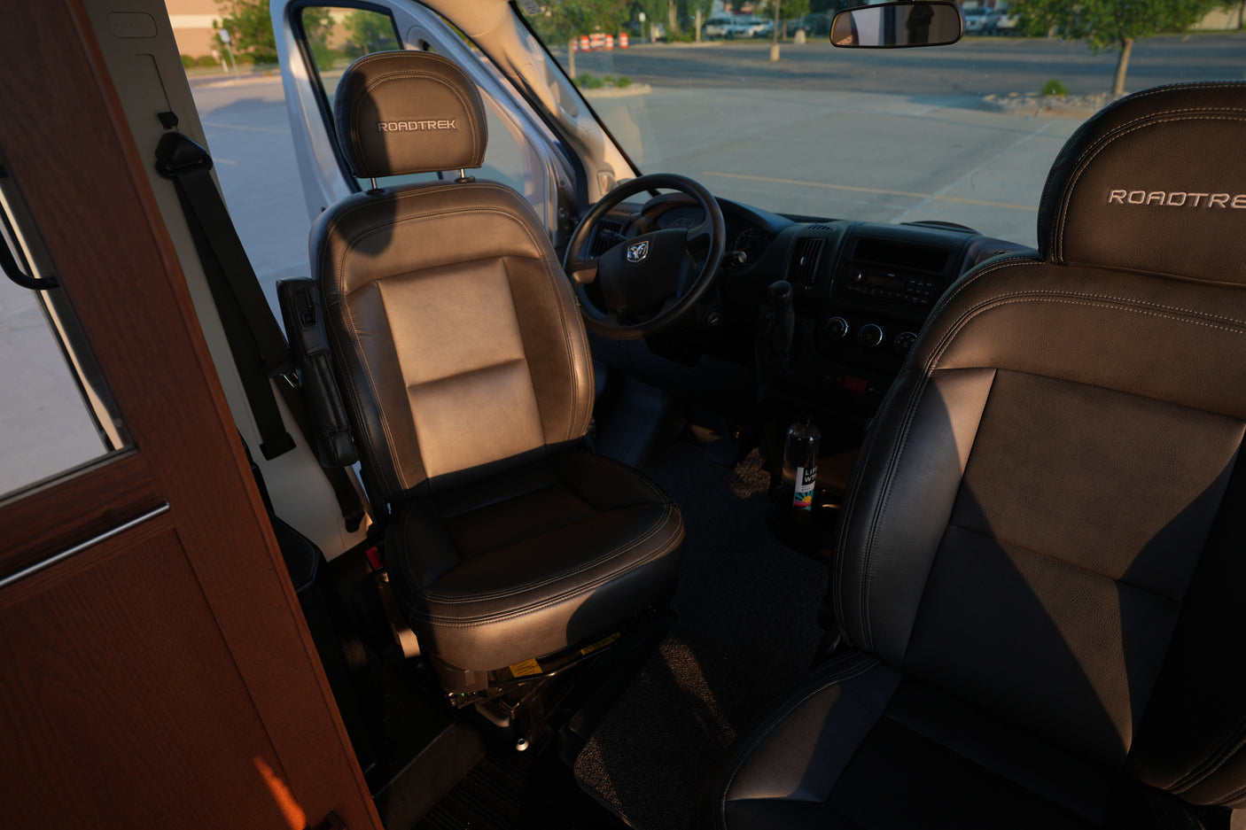 Interior of this RV rental features Roadtrek branded front seats, steering wheel, and dashboard, ready for your next adventure.