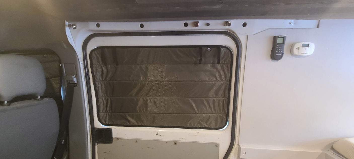 RV rental interior featuring a window with insulated cover, remote, and carbon monoxide detector for comfort and safety.