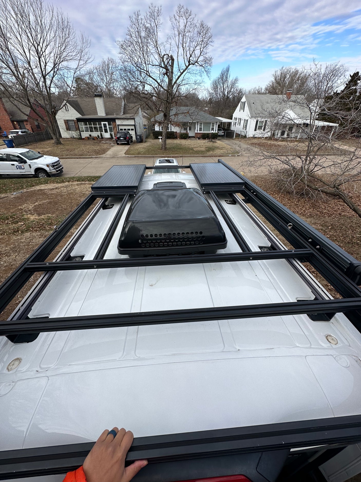 Top-down view of an RV rental van, showcasing its rooftop solar panels, AC unit, and robust roof rack system.