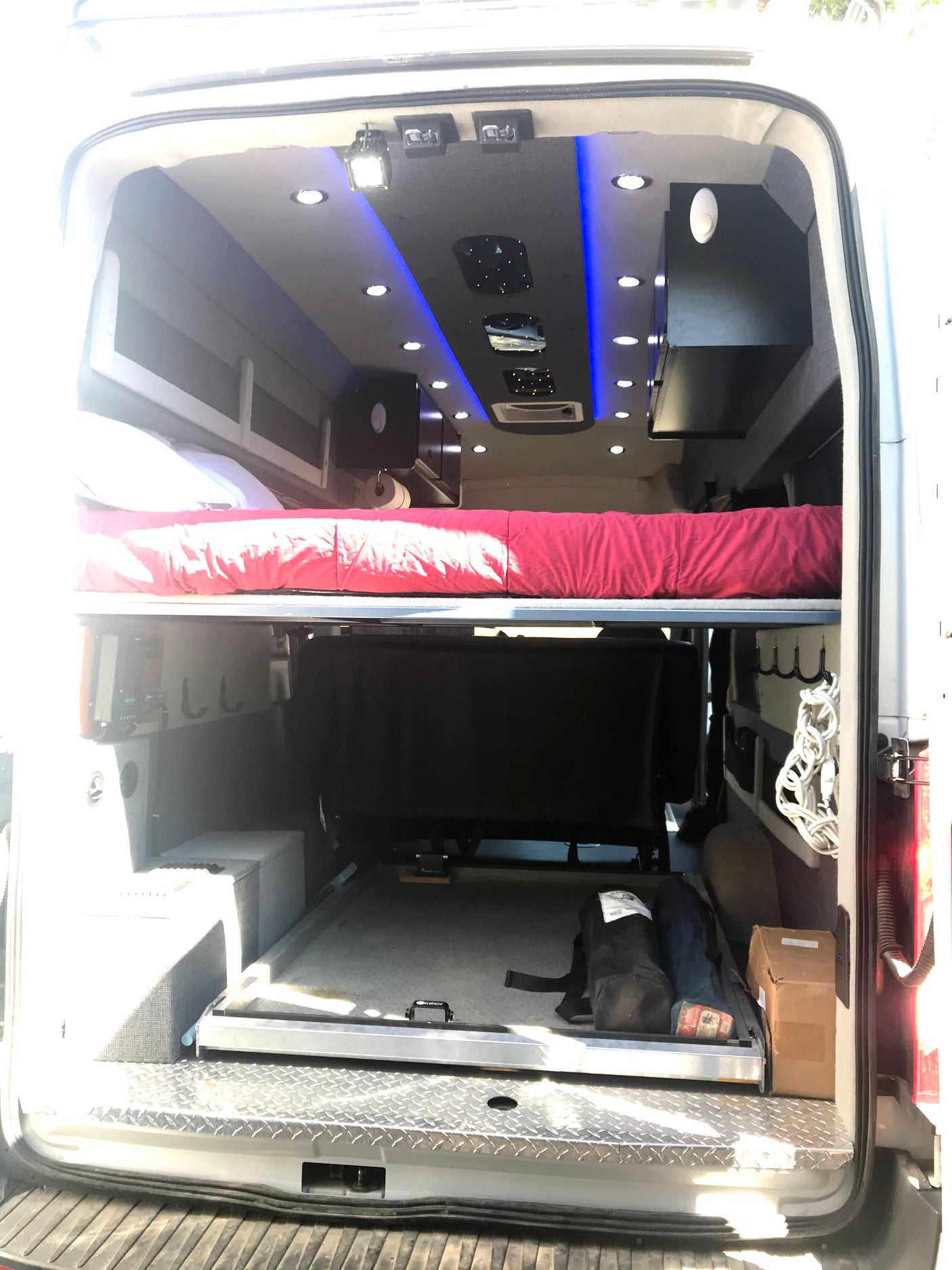 RV rental: Inside a custom camper van conversion with a comfortable sleeping area, compact kitchenette, and vibrant LED lighting.