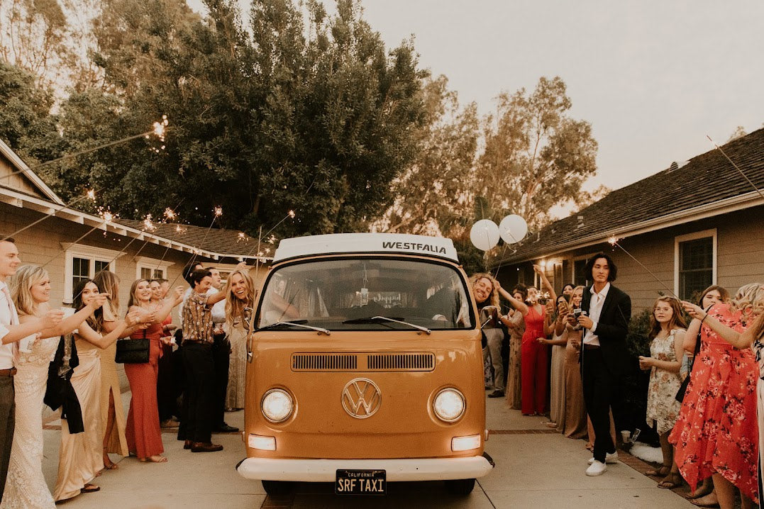 Vintage VW bus RV rental. Friends with sparklers cheer as two people smile from inside the festive camper van. — photo 17