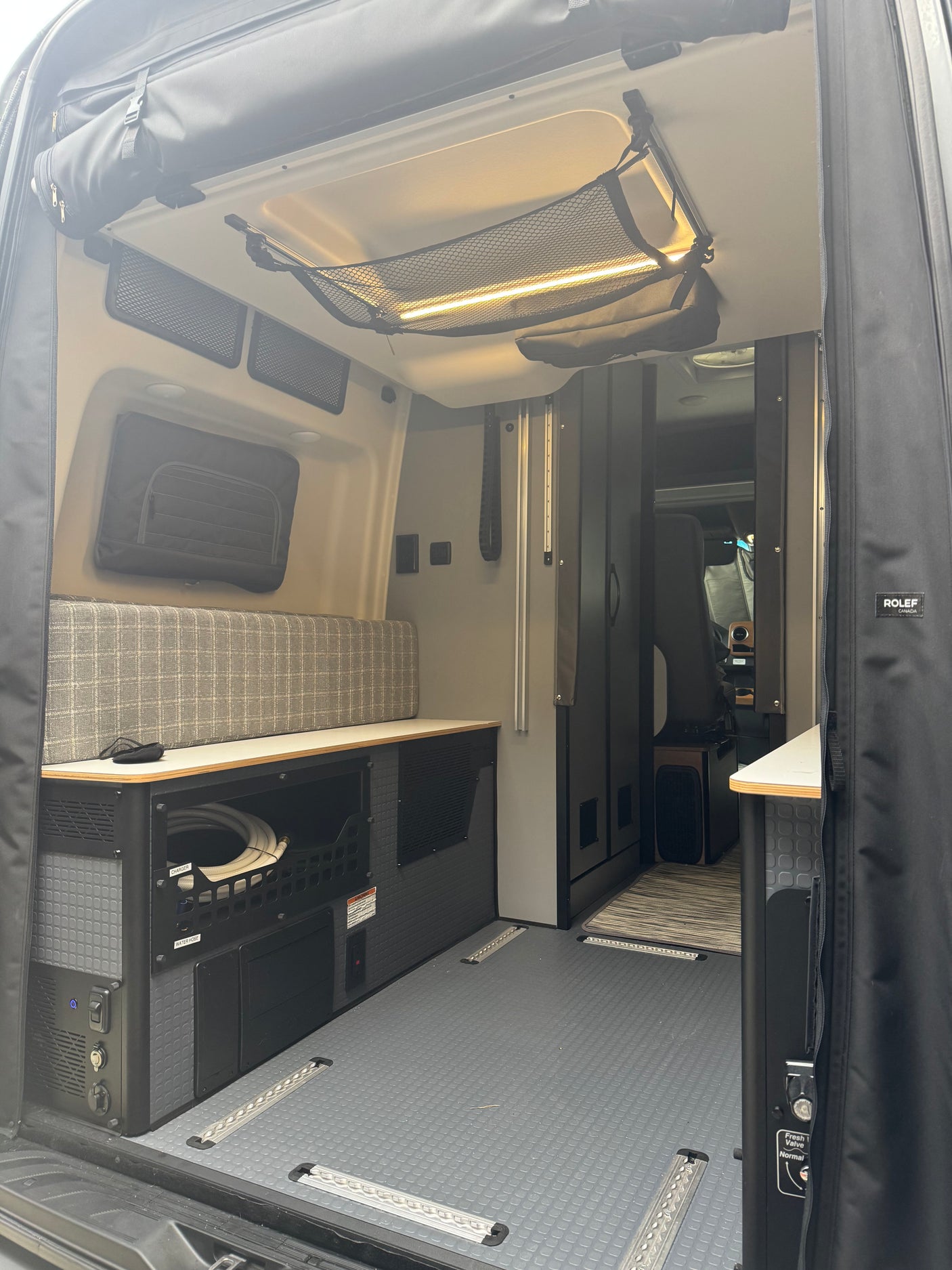 Spacious RV rental interior featuring bench seating, organized utility storage, durable floor, and ceiling net for comfy mobile living.