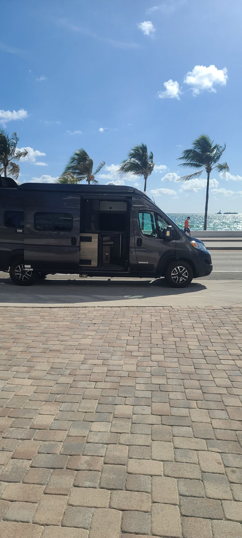 parked on a street in front of a grand building.|An RV rental van's inviting interior: driver's seat