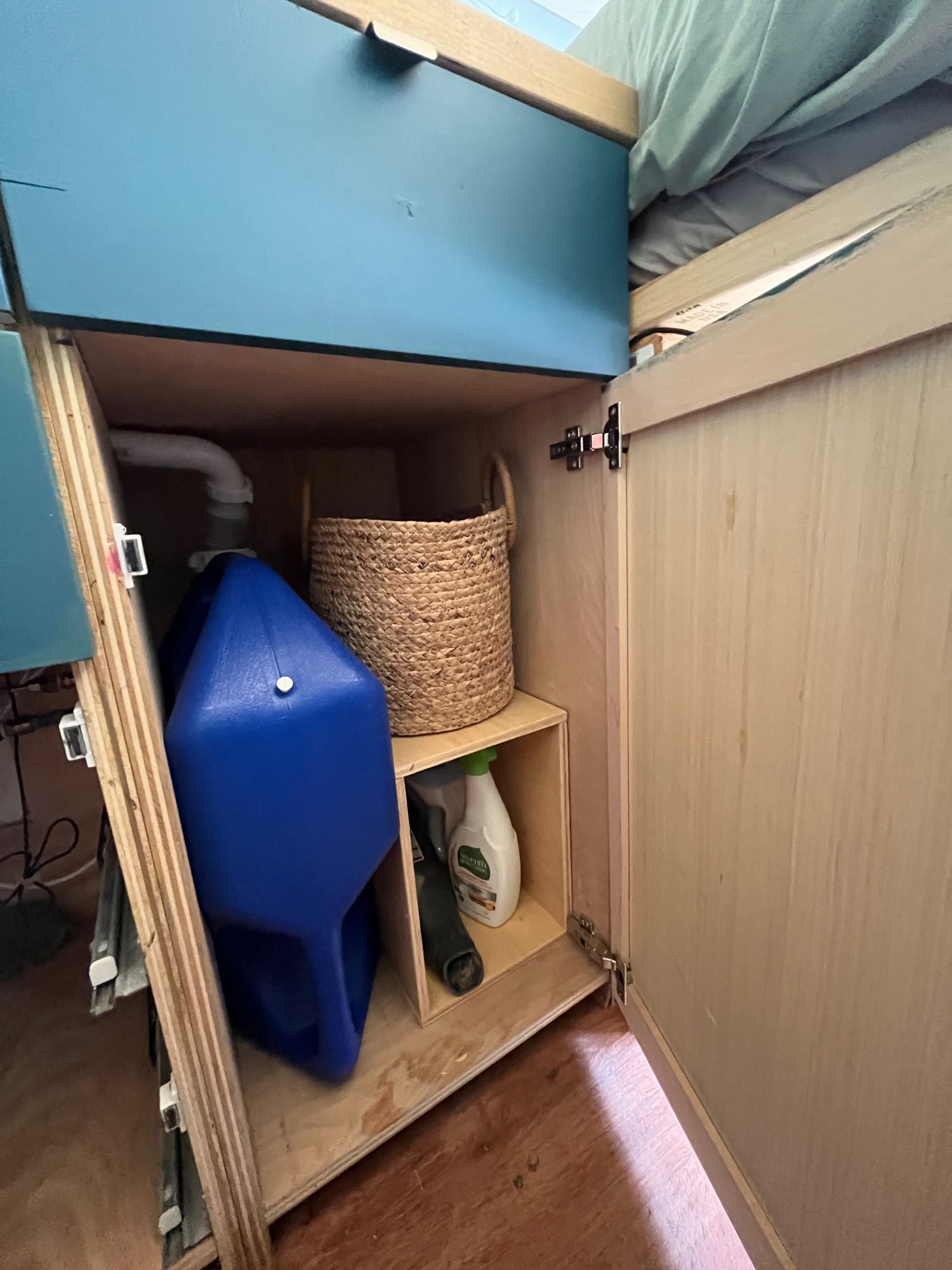 and a bed. Green tree view outside.|Open back doors of an rv rental conversion van reveal bed