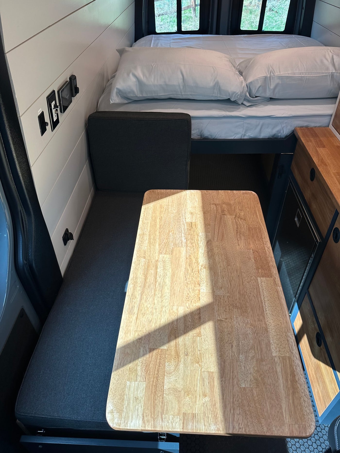 Bright RV rental interior showing a versatile dinette table, bench seat, and elevated bed area. — photo 5