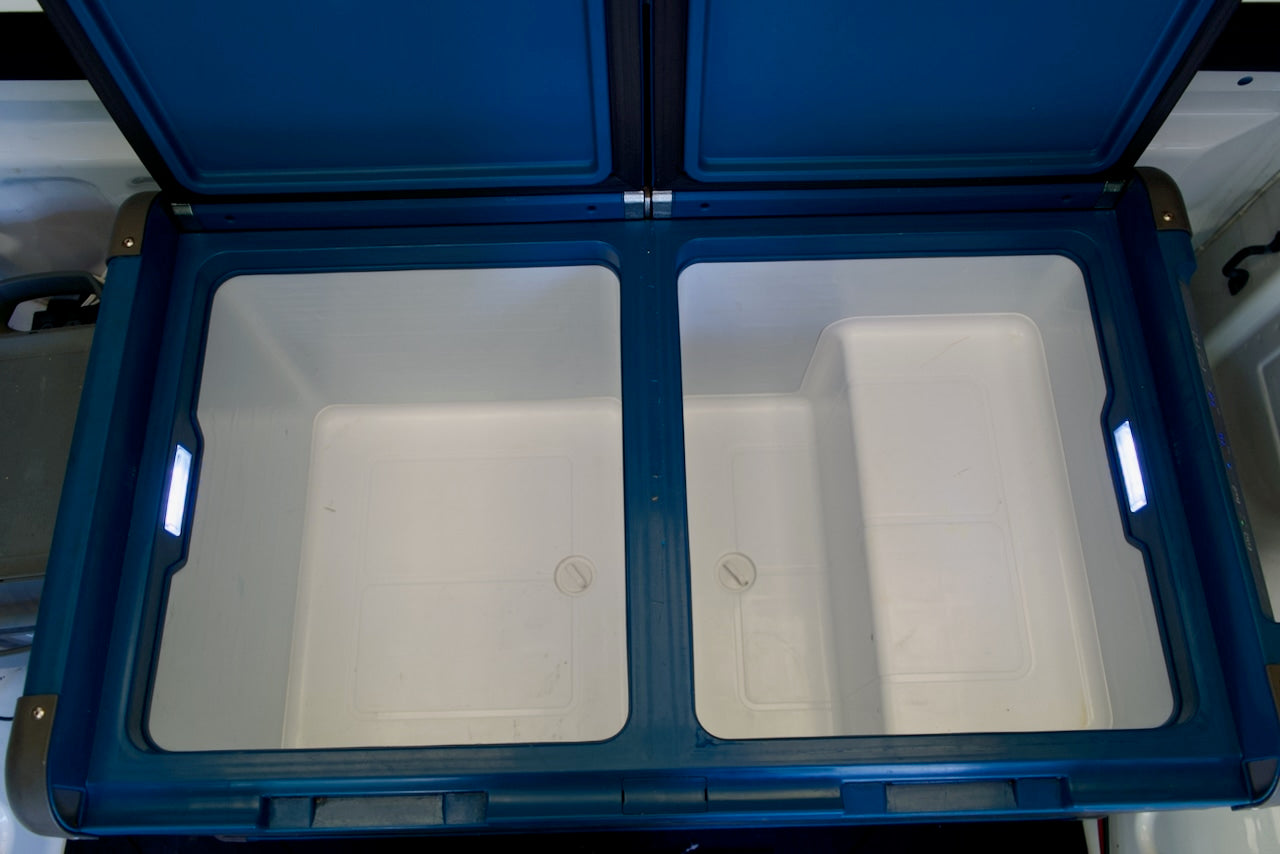 Empty blue and white dual-zone portable refrigerator with LED lights, ideal for your next rv rental trip's food storage.