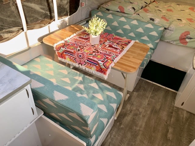 and cabinet with a 'No Smoking' sign.|Renovated rv rental camper interior. Bright dinette with teal geometric cushions
