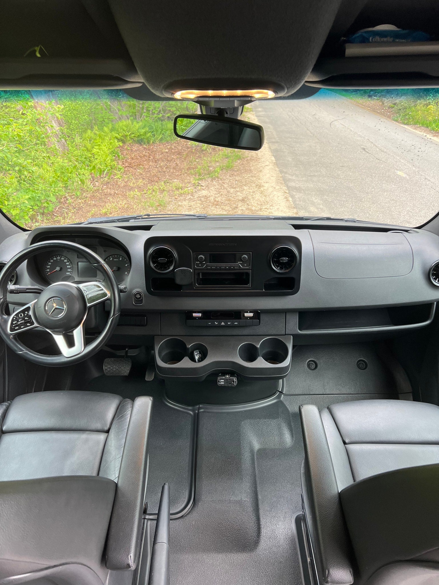 Inside a Mercedes Sprinter van, perfect for an RV rental adventure. Driver's view of the dashboard, steering wheel, and front cabin.