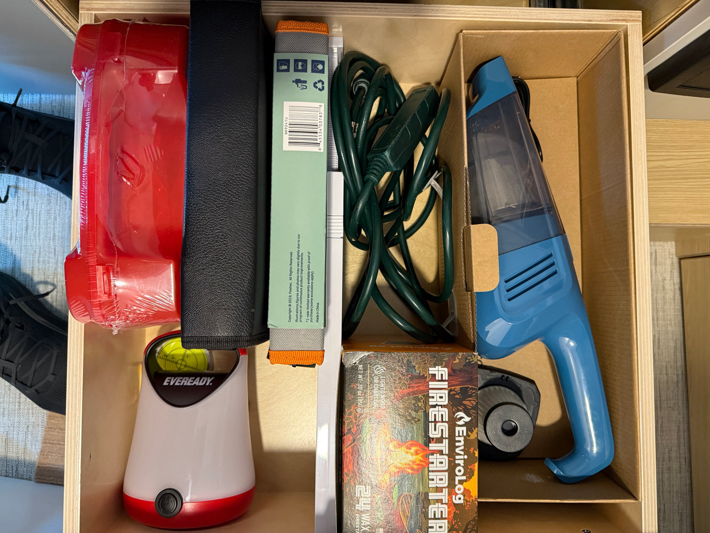 An RV rental drawer, neatly organized with camping essentials: firestarters, handheld vacuum, lantern, and various tools.