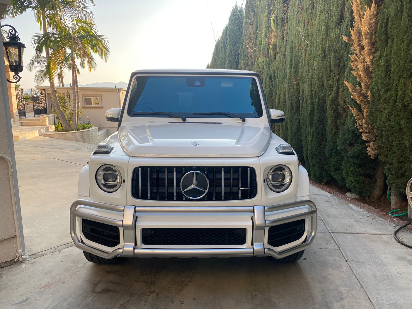 White Mercedes-Benz G-Wagen SUV parked on a sunny driveway. A luxury vehicle, far from an RV rental, ready for adventures.