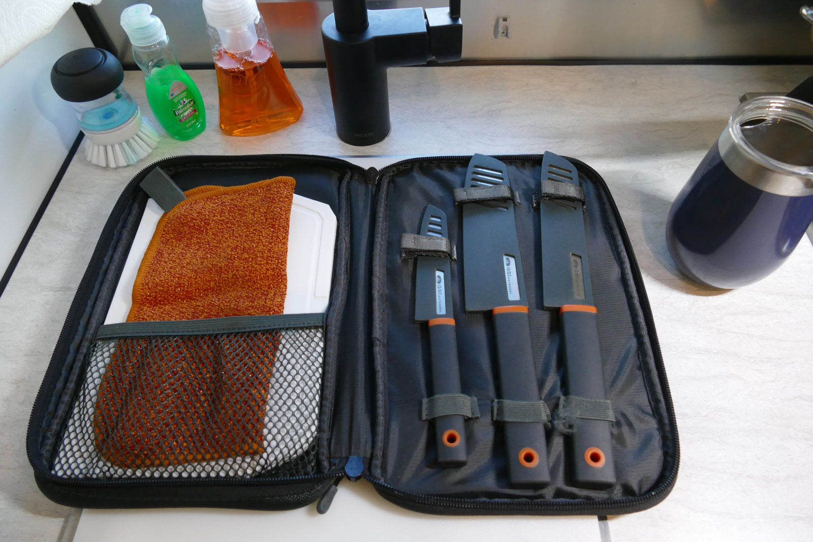 RV rental kitchen essentials: GSI Outdoors knife set, scrubber, cutting board, and dish soap for easy camp cooking.