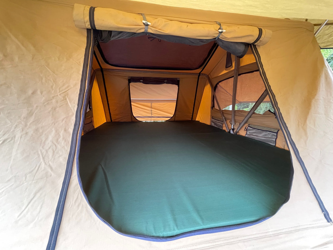 Inside an RV rental rooftop tent: Spacious interior with green mattress. Perfect for camping adventures.