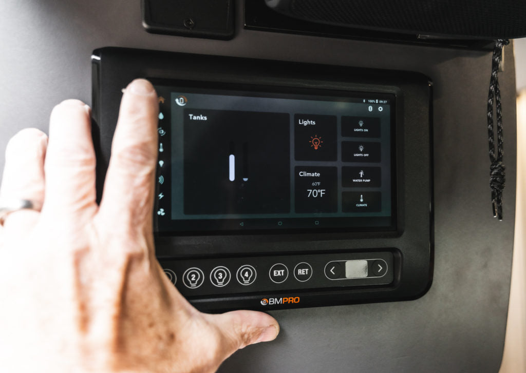 User interacts with an RV rental's BMPRO smart control panel, managing tank levels, lights, and climate settings.