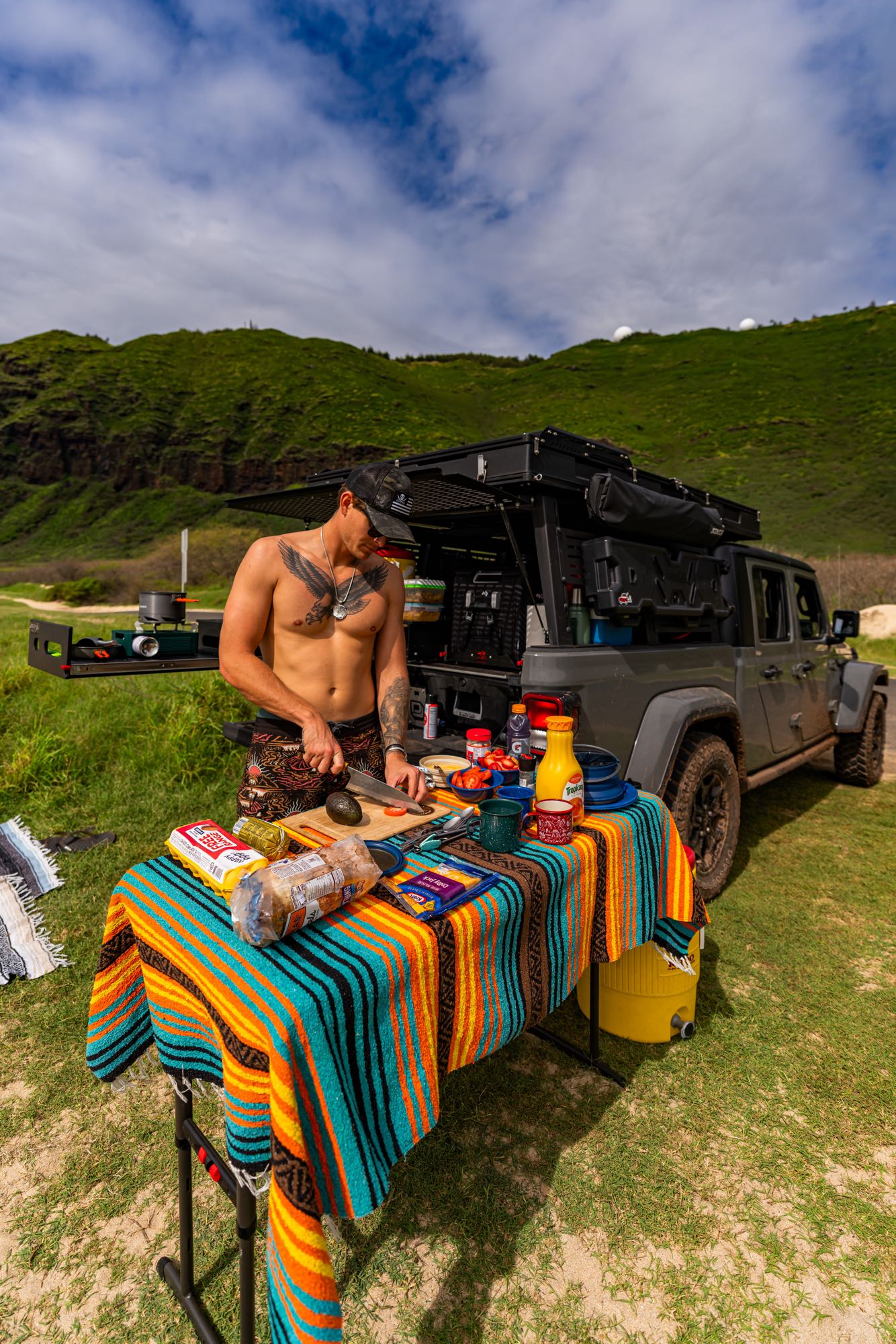 A man cooks outdoors from his overlanding vehicle, an ideal RV rental for scenic adventures. Fresh food prep.