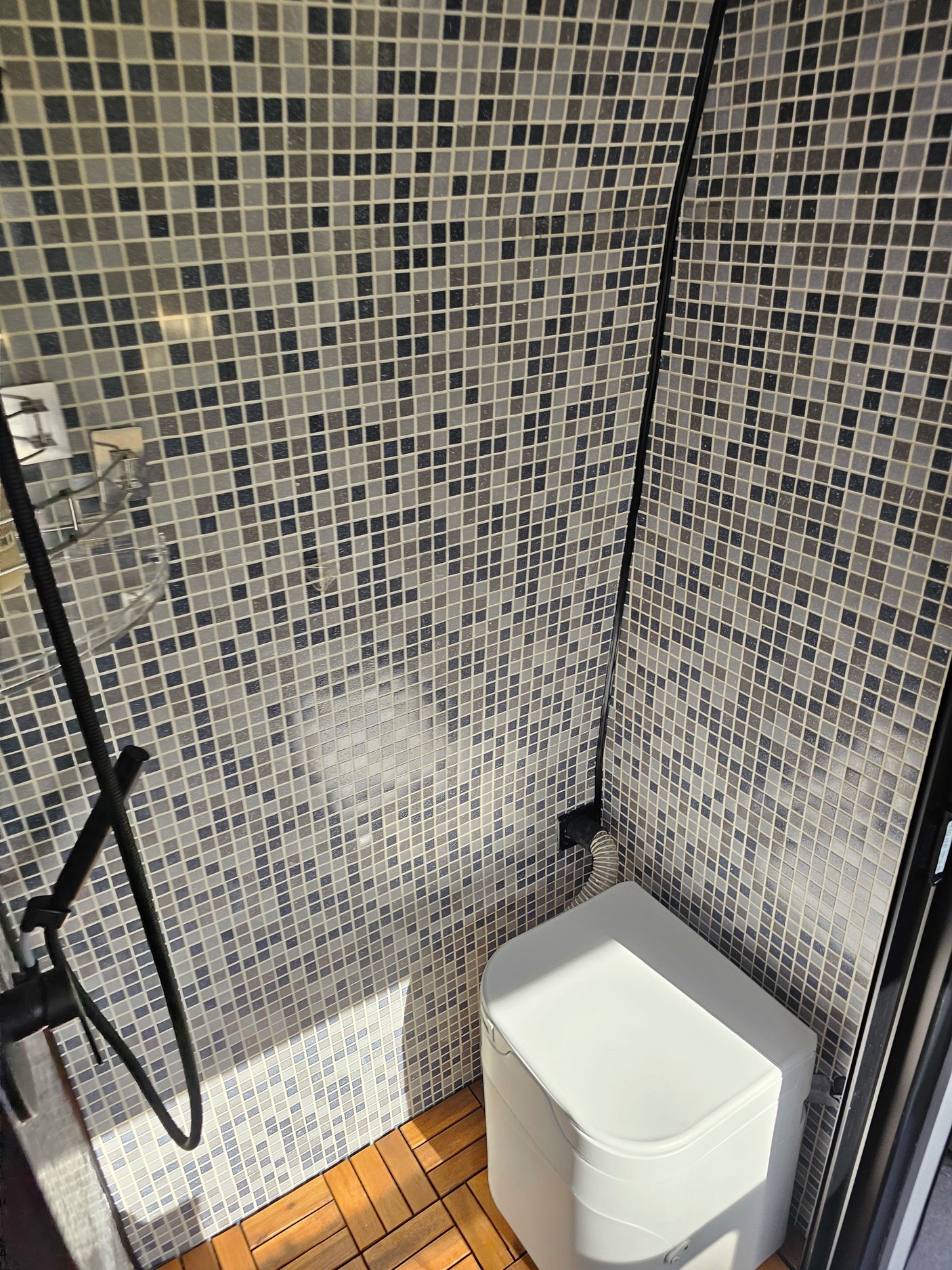 Your next RV rental's compact bathroom: mosaic tiles, composting toilet, shower. Perfect for camping trips.